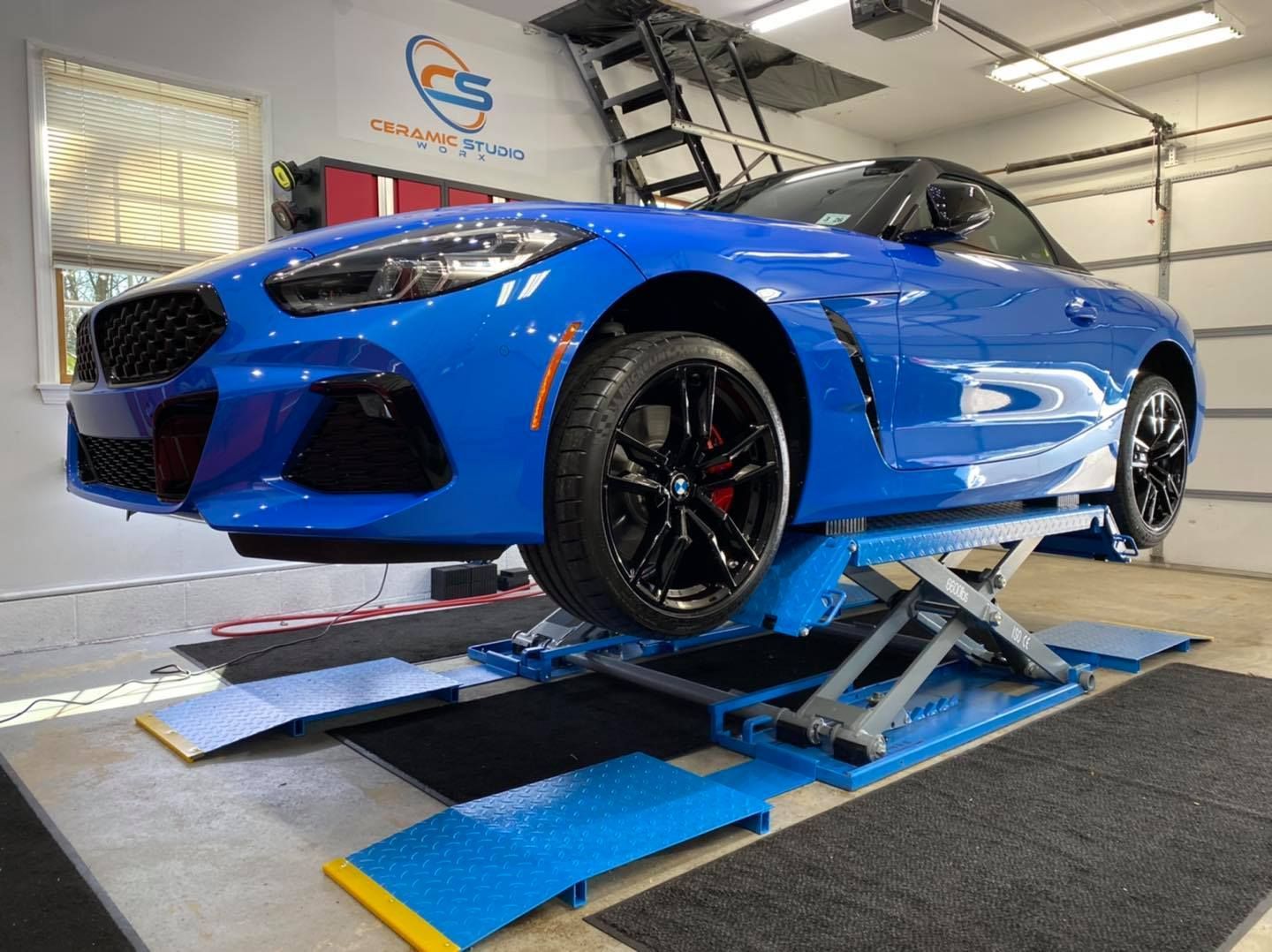 Blue BMW sports car on a blue scissor lift in a garage.