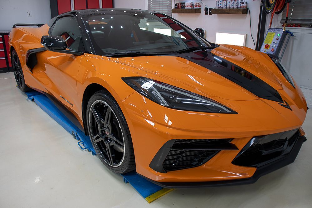 Orange sports car with black accents parked indoors.