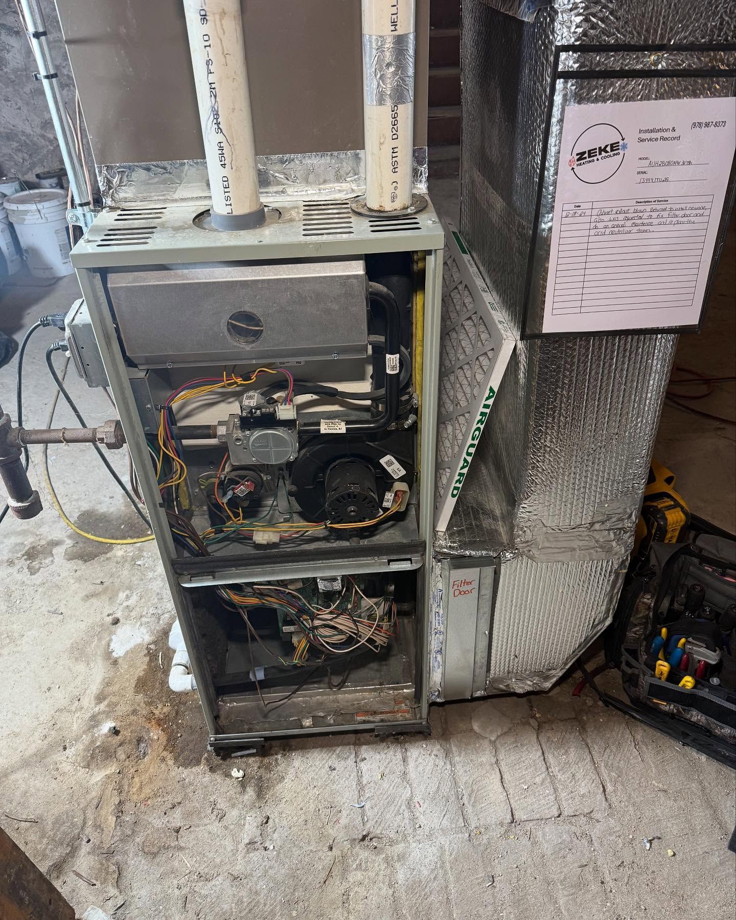A dirty air conditioner is sitting on the floor in a basement.