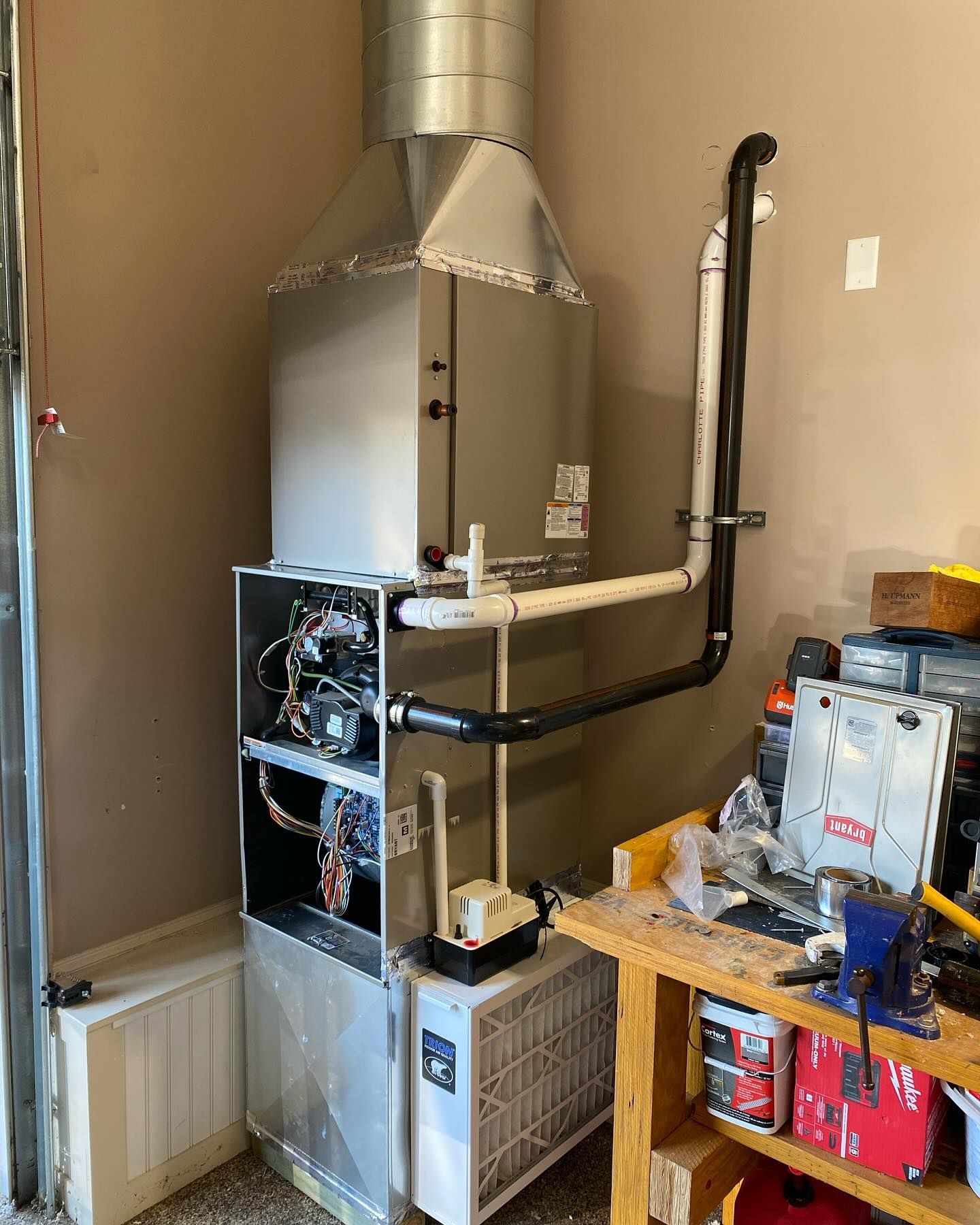 A gas heater is sitting in a garage next to a wooden workbench.