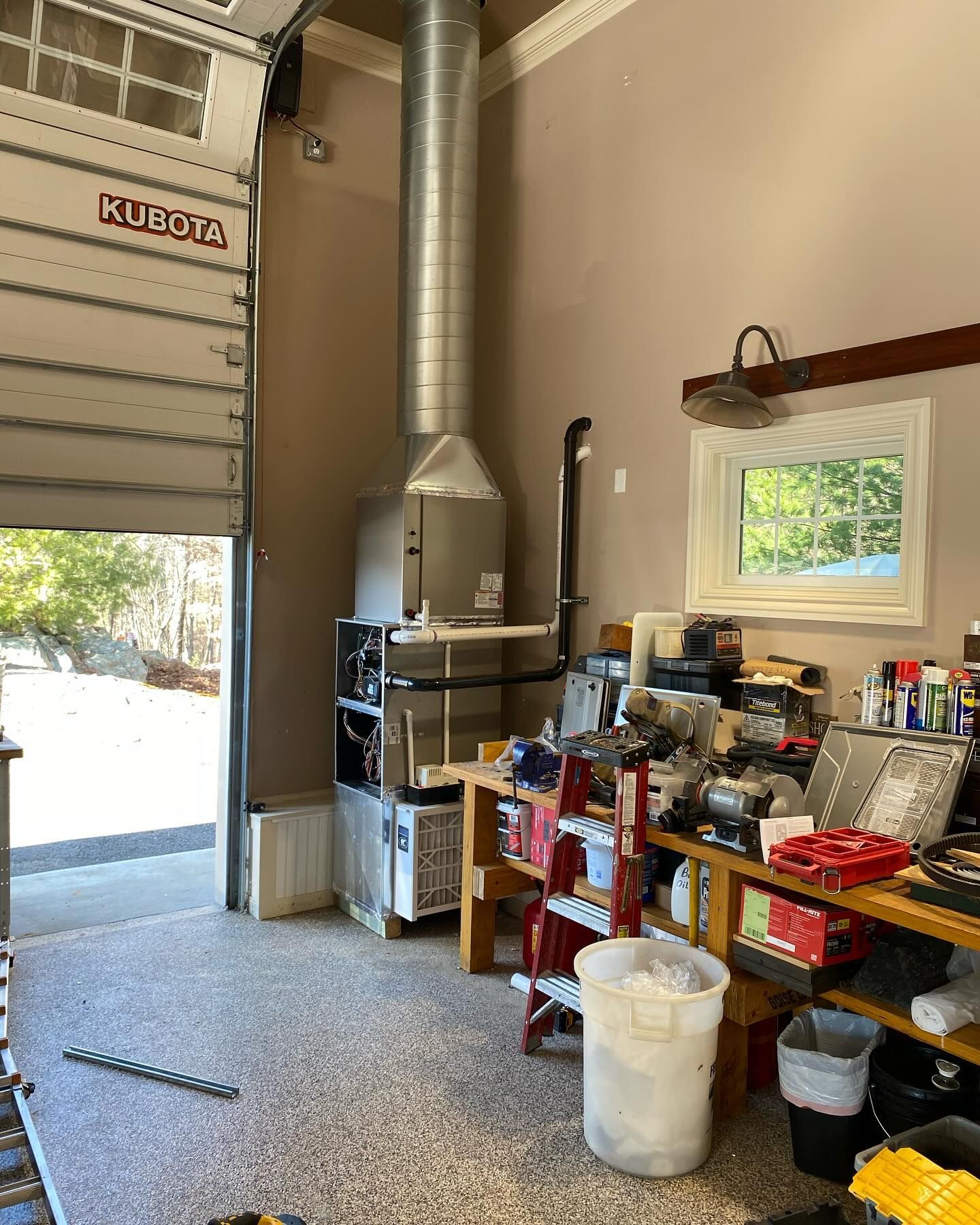 A garage with a garage door open and a lot of tools on the floor.