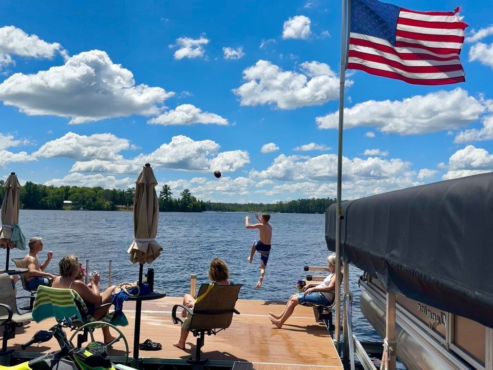 A group of people are sitting on a dock overlooking a lake.
