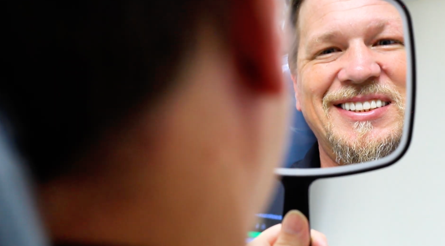 Smiling dental patient staring in a mirror