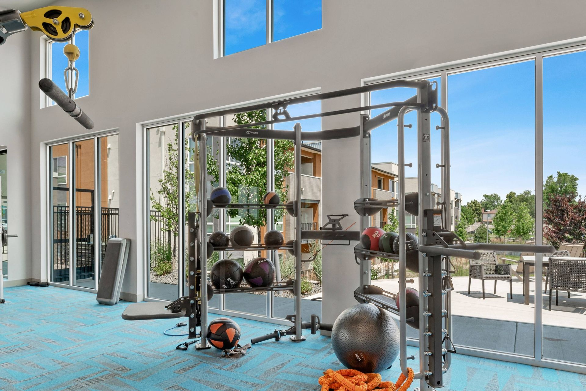 Avail Modern Living Apartments' gym has a weightlifting station, exercise balls, and large windows with patio views.