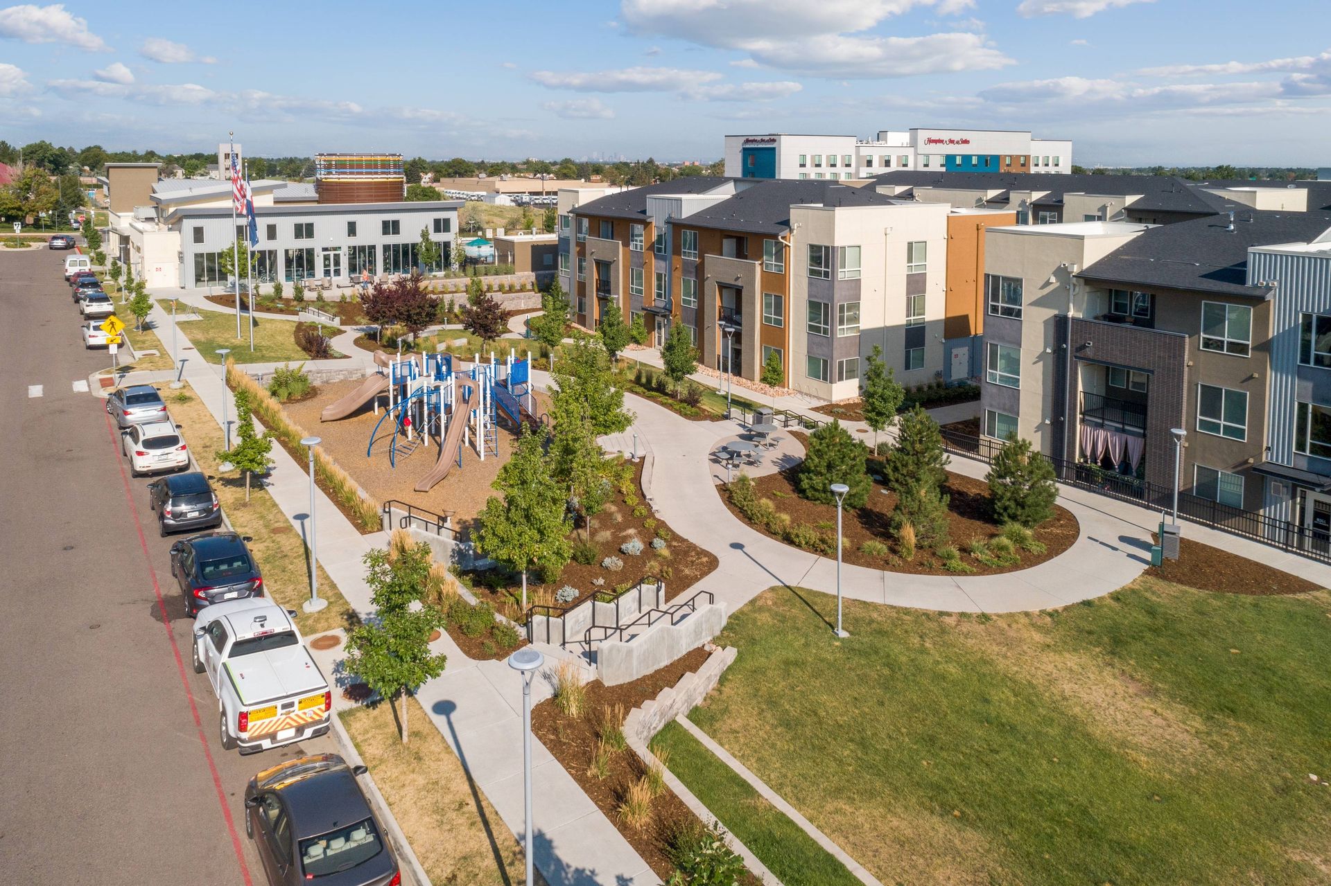 An aerial view of Avail Modern Living Apartments showcases colorful buildings, a playground, and landscaped green space.