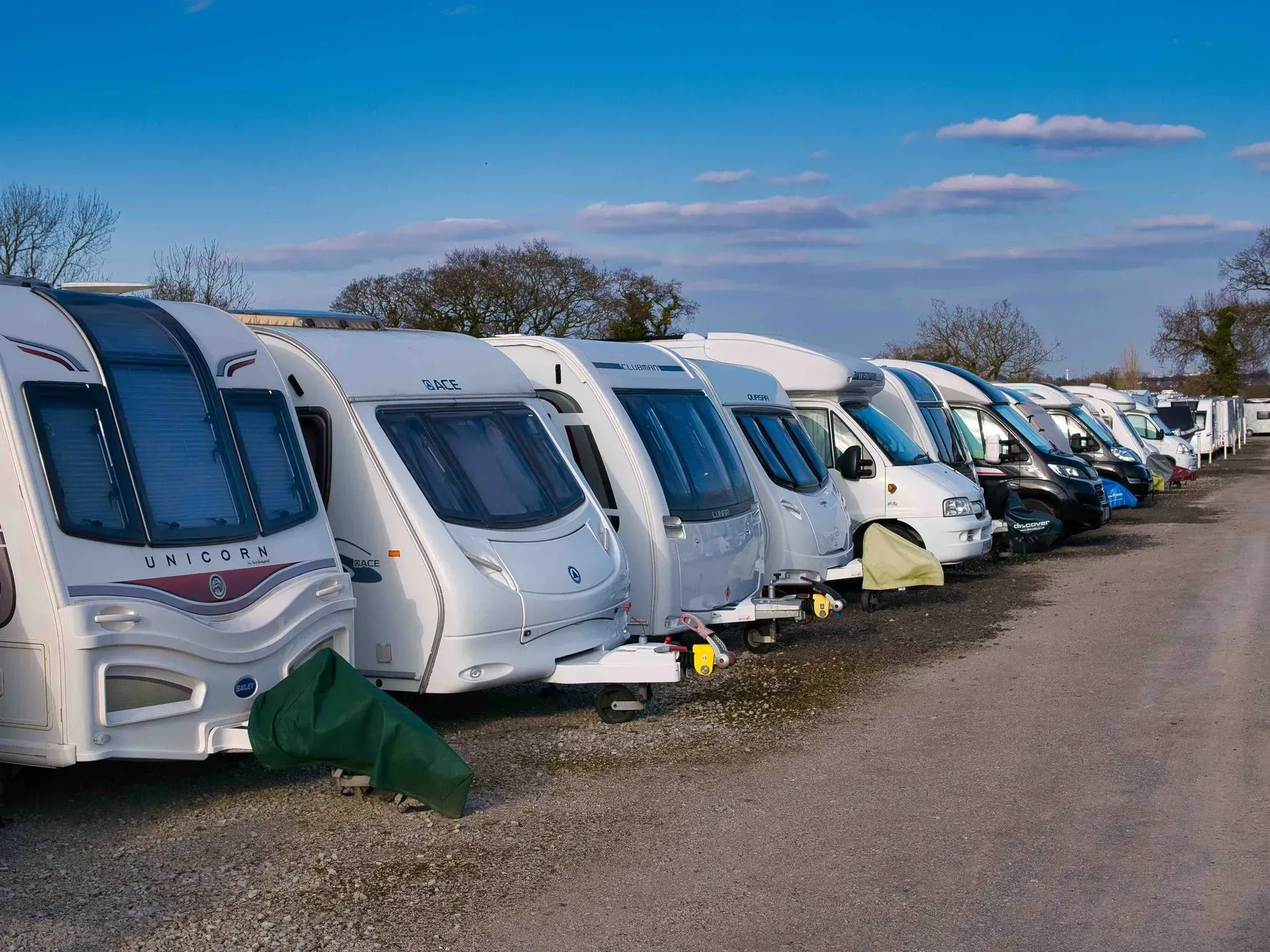 A row of caravans parked next to each other on a gravel road.