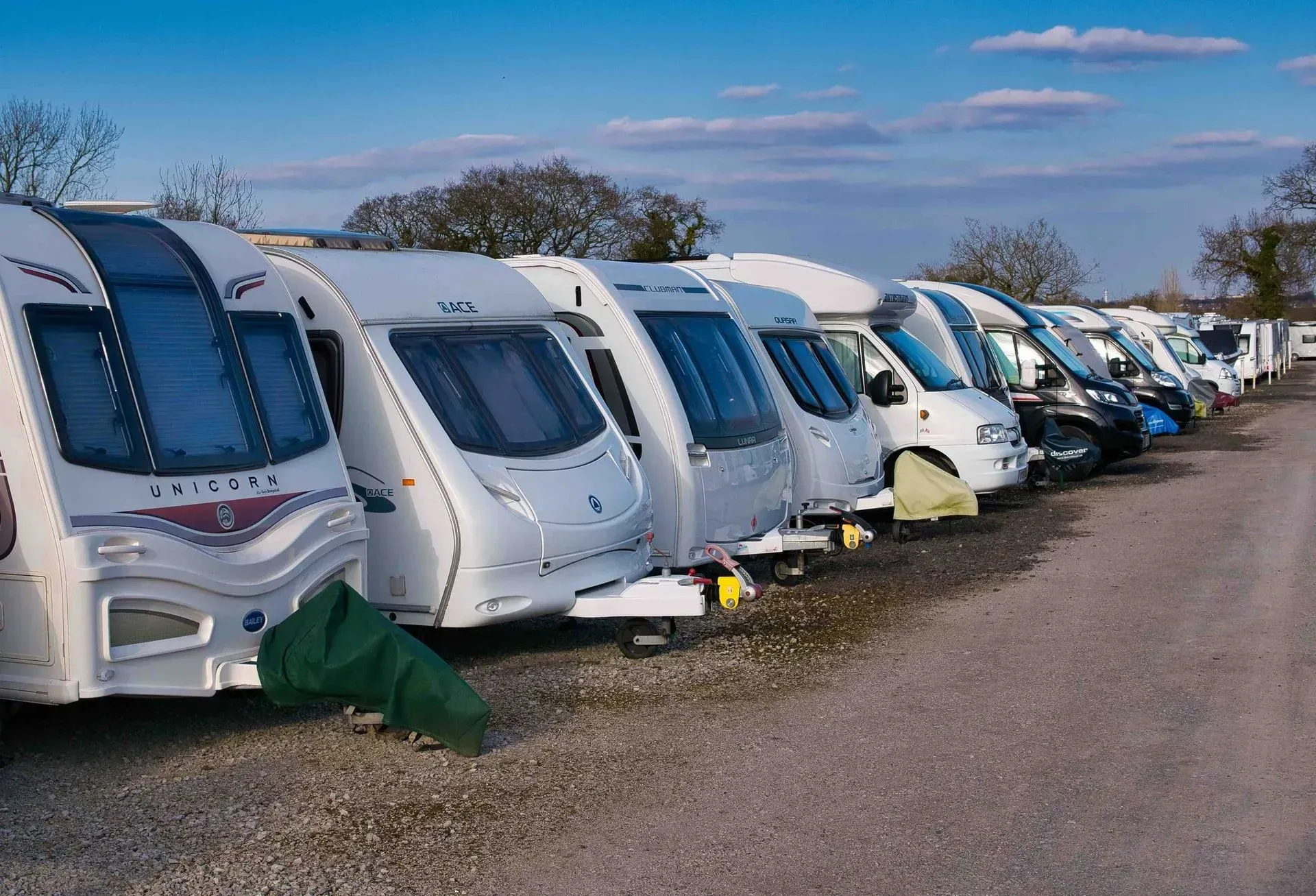 A row of caravans parked next to each other on a gravel road.