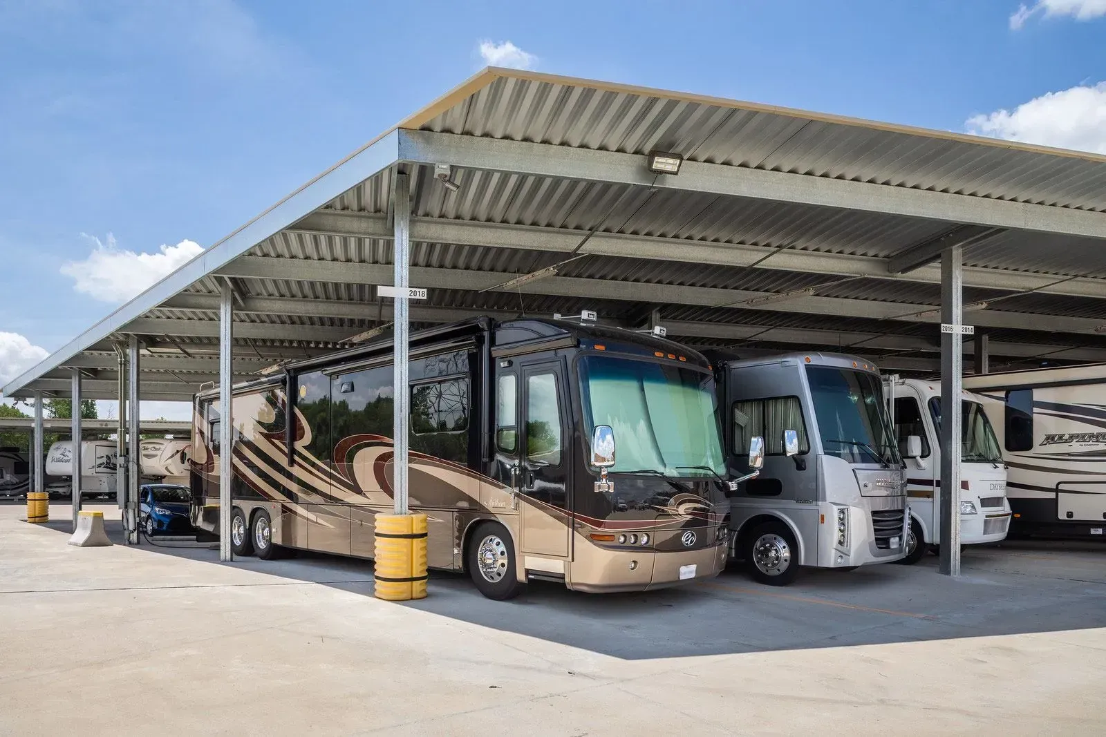 A row of recreational vehicles are parked under a covered area.