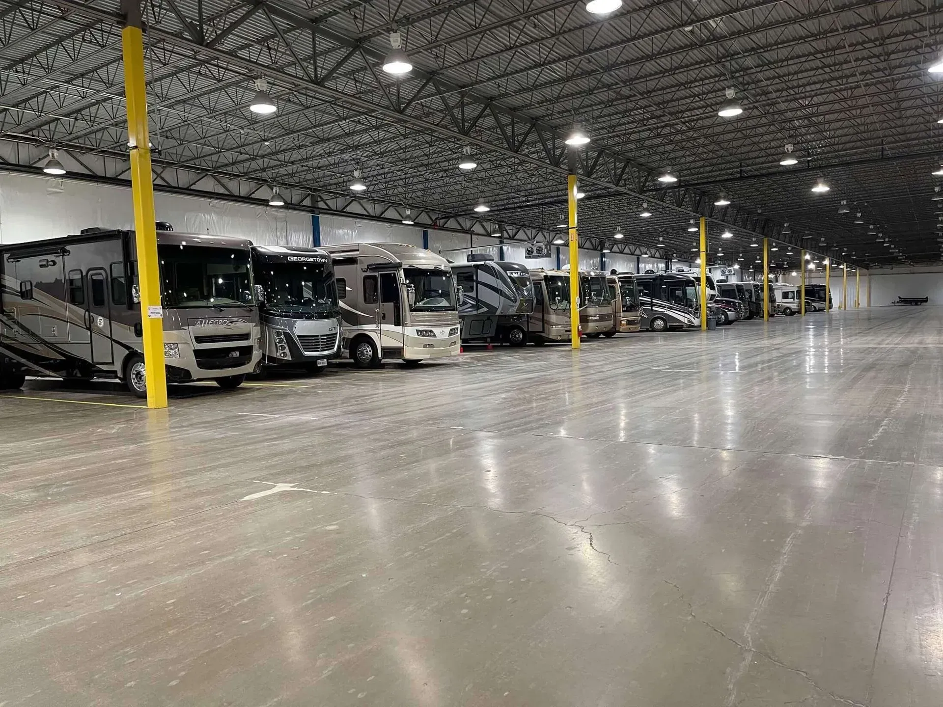 A large warehouse filled with rvs parked in a row.