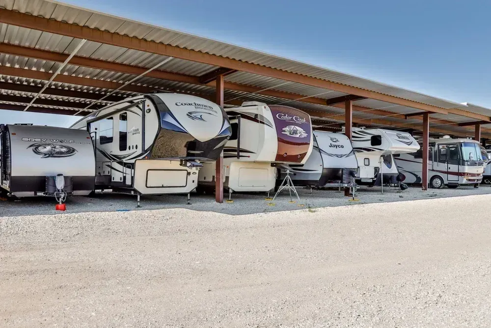 A row of recreational vehicles are parked under a covered area.