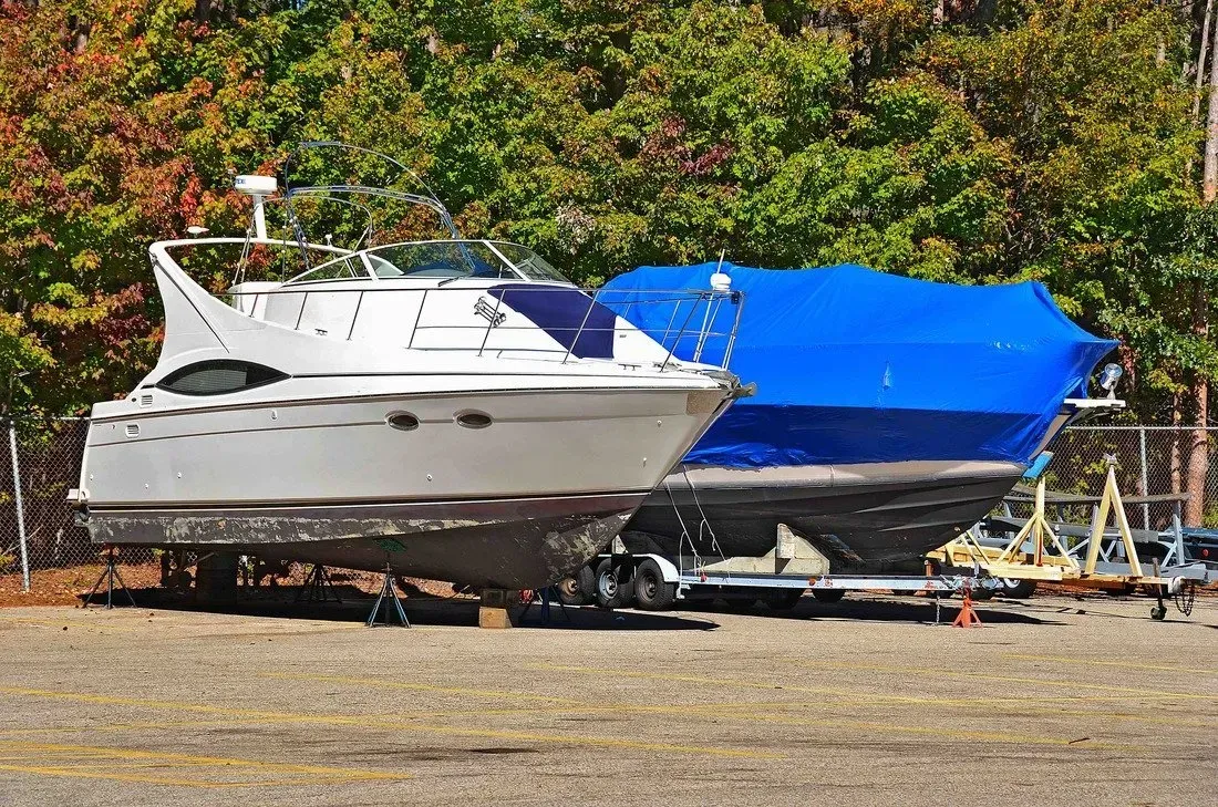 Two boats are parked next to each other in a parking lot.