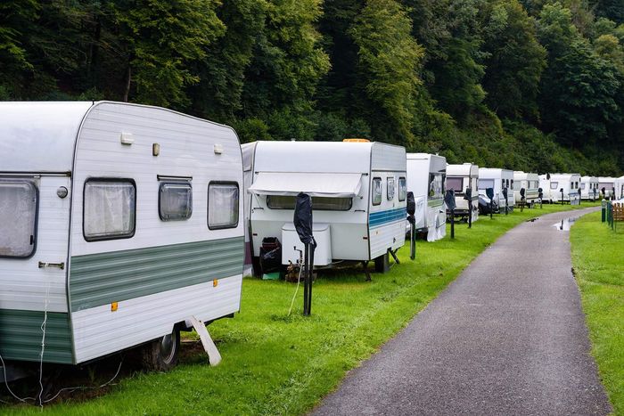 A row of caravans parked on the side of a dirt road.