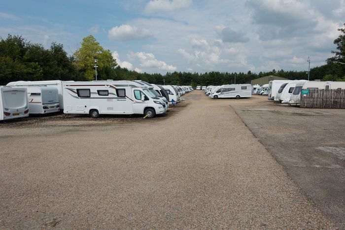 A lot of rvs are parked in a gravel lot