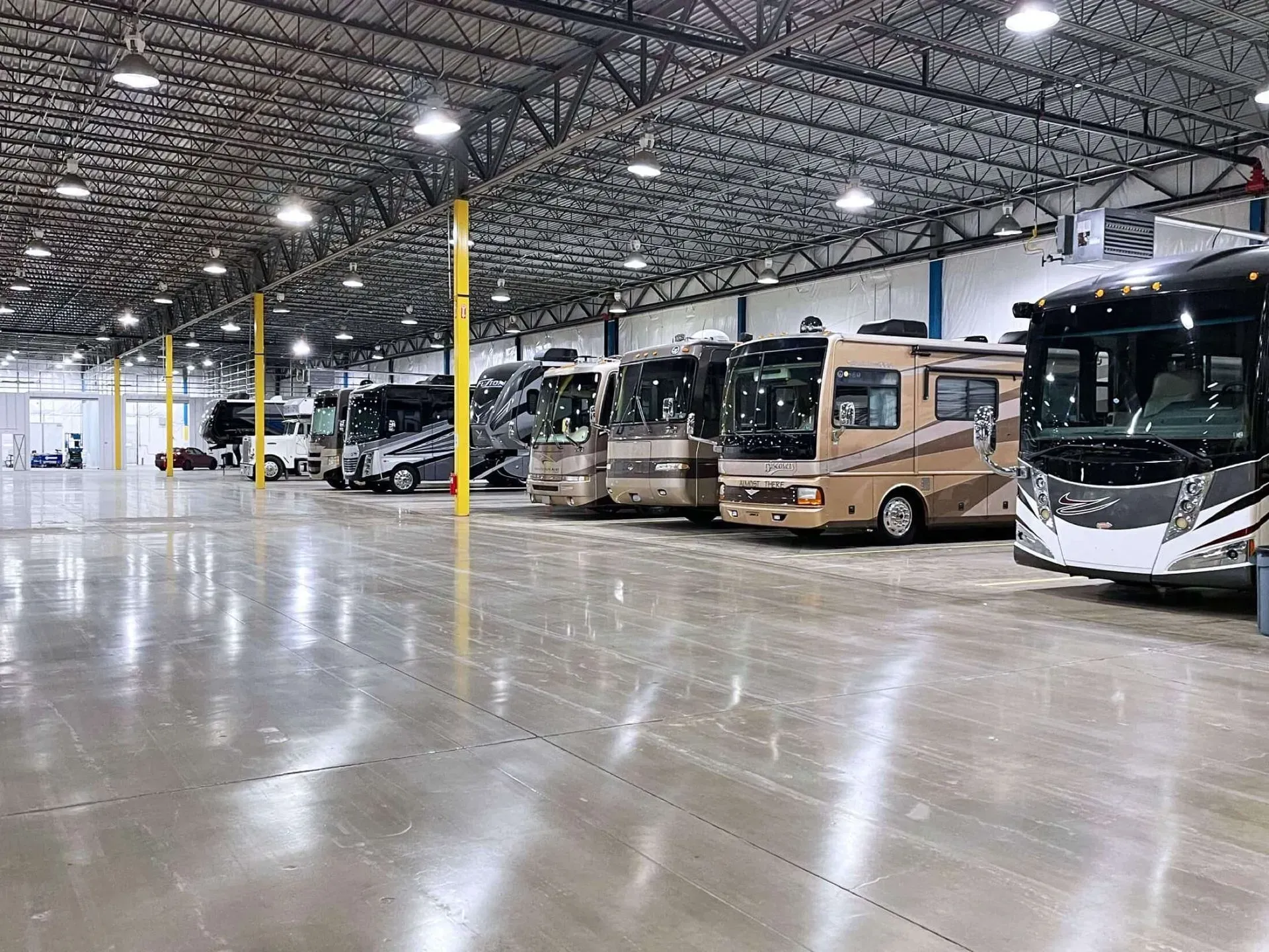 A row of rvs are parked in a large warehouse.