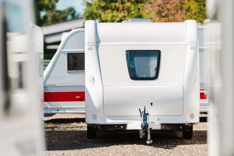 A white camper trailer is parked in a parking lot.