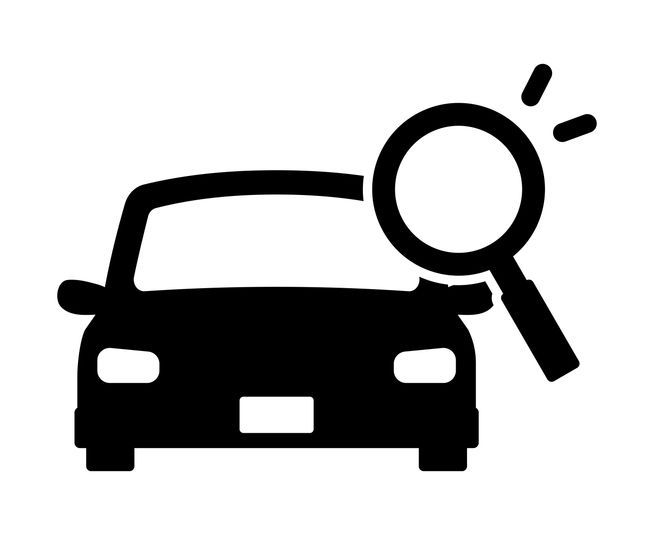 A man is looking under the hood of a car in a garage.