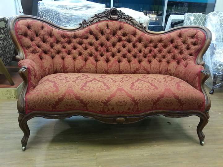 A red couch is sitting on a wooden floor in a room.