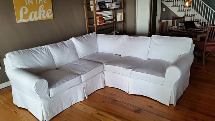 A white sectional couch in a living room with a sign that says in the lake