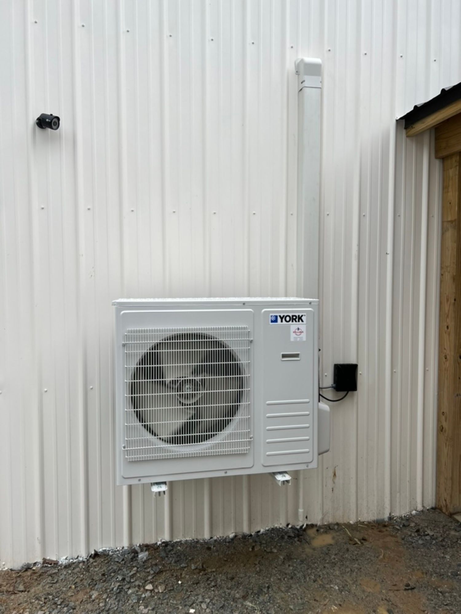 A white air conditioner is mounted on the side of a building.