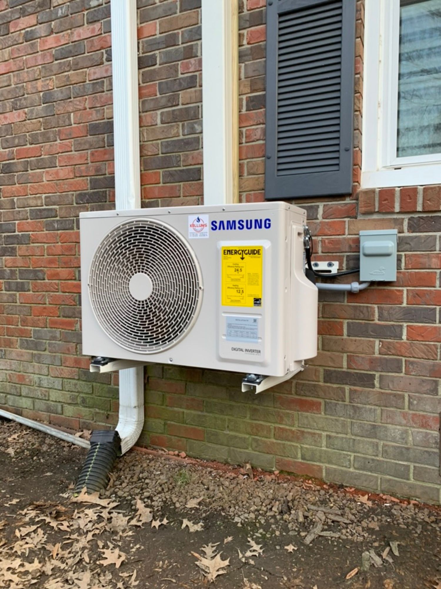 A samsung air conditioner is mounted on the side of a brick building.