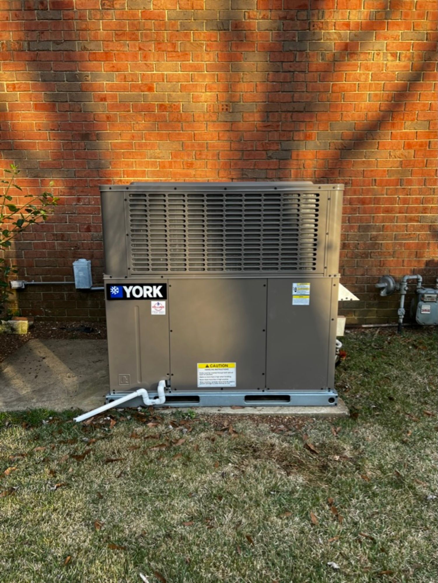 A york air conditioner is sitting on the side of a brick building.