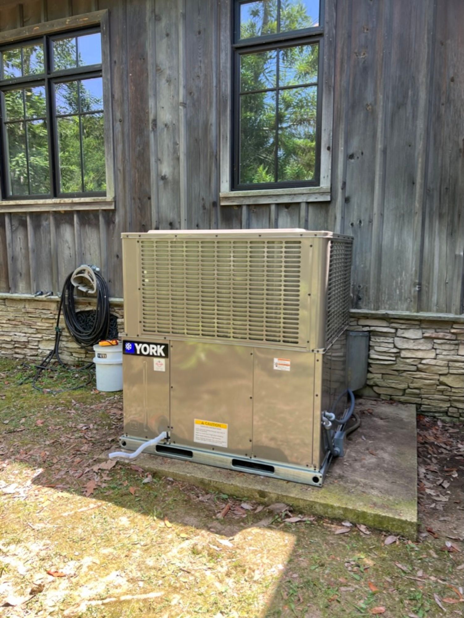 A york air conditioner is sitting outside of a wooden building.