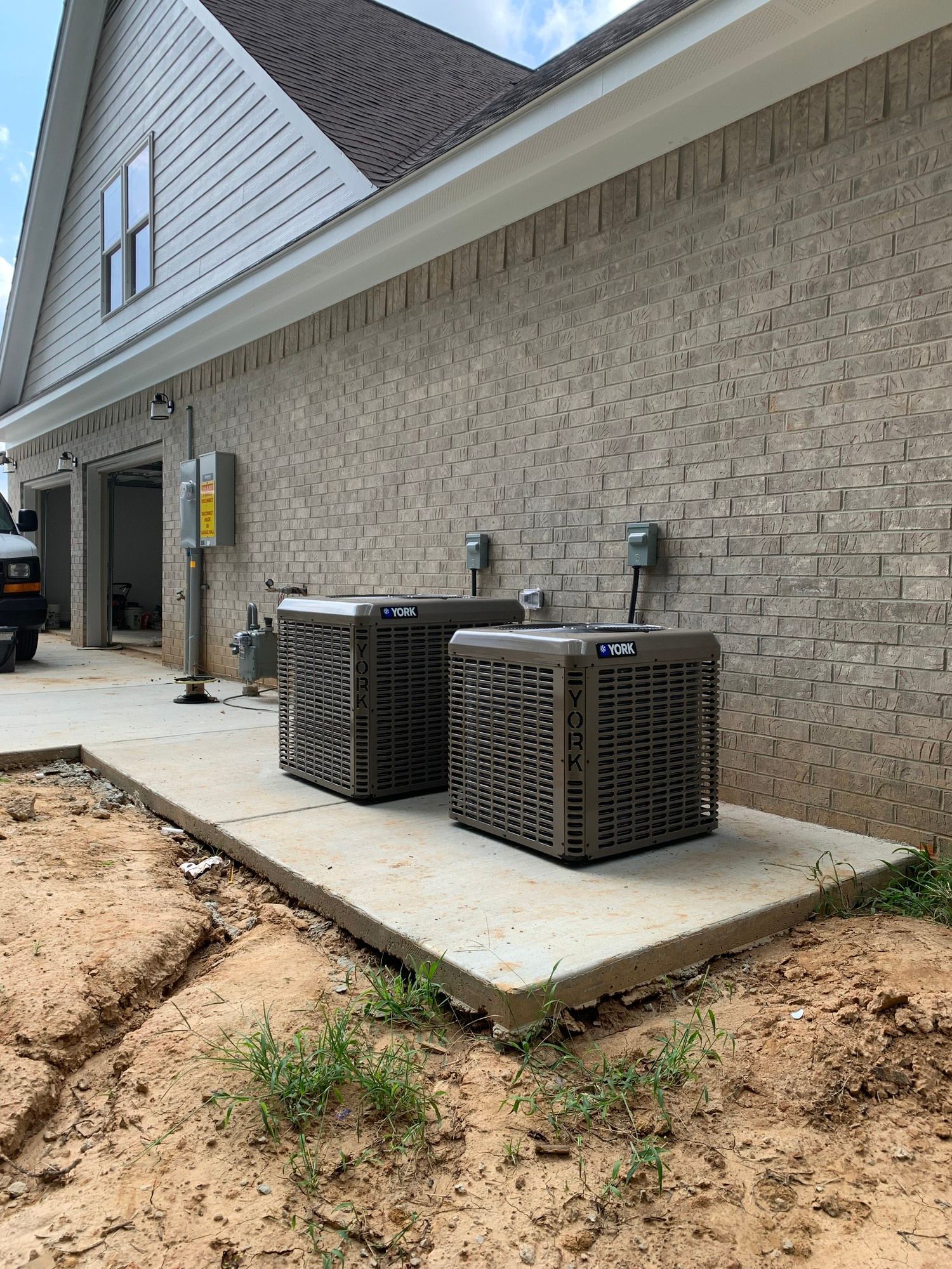Two air conditioners are sitting on the side of a brick building.