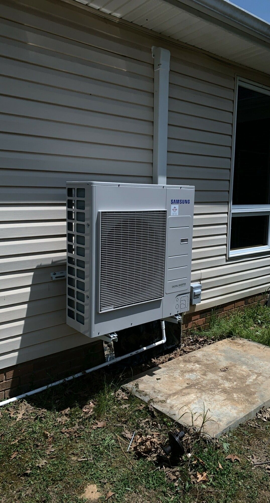 A large air conditioner is mounted on the side of a house.