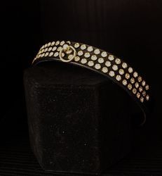 A black belt with gold studs is sitting on top of a black block.