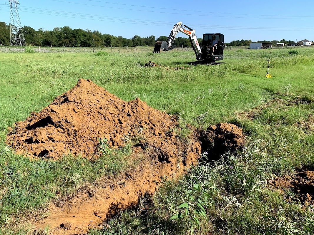 A bulldozer is digging a hole in a grassy field.