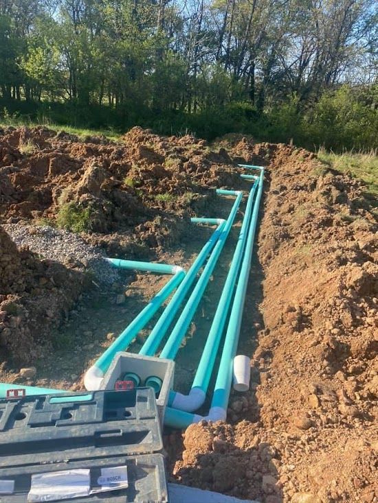 A bunch of green pipes are laying in the dirt