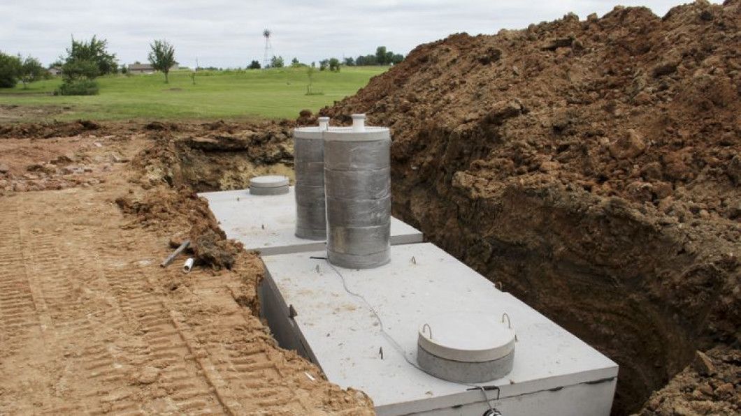 A septic tank is sitting in the dirt next to a pile of dirt.