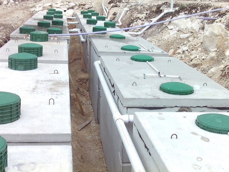 A row of concrete septic tanks with green lids