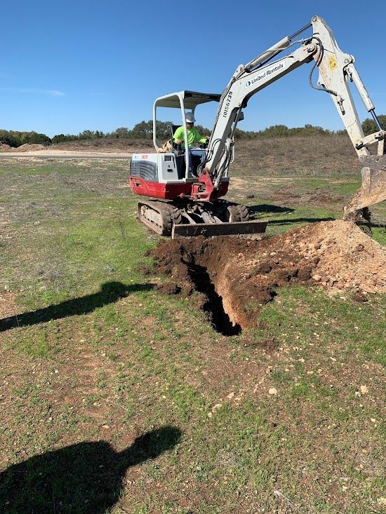 A man is driving a small excavator in a field.
