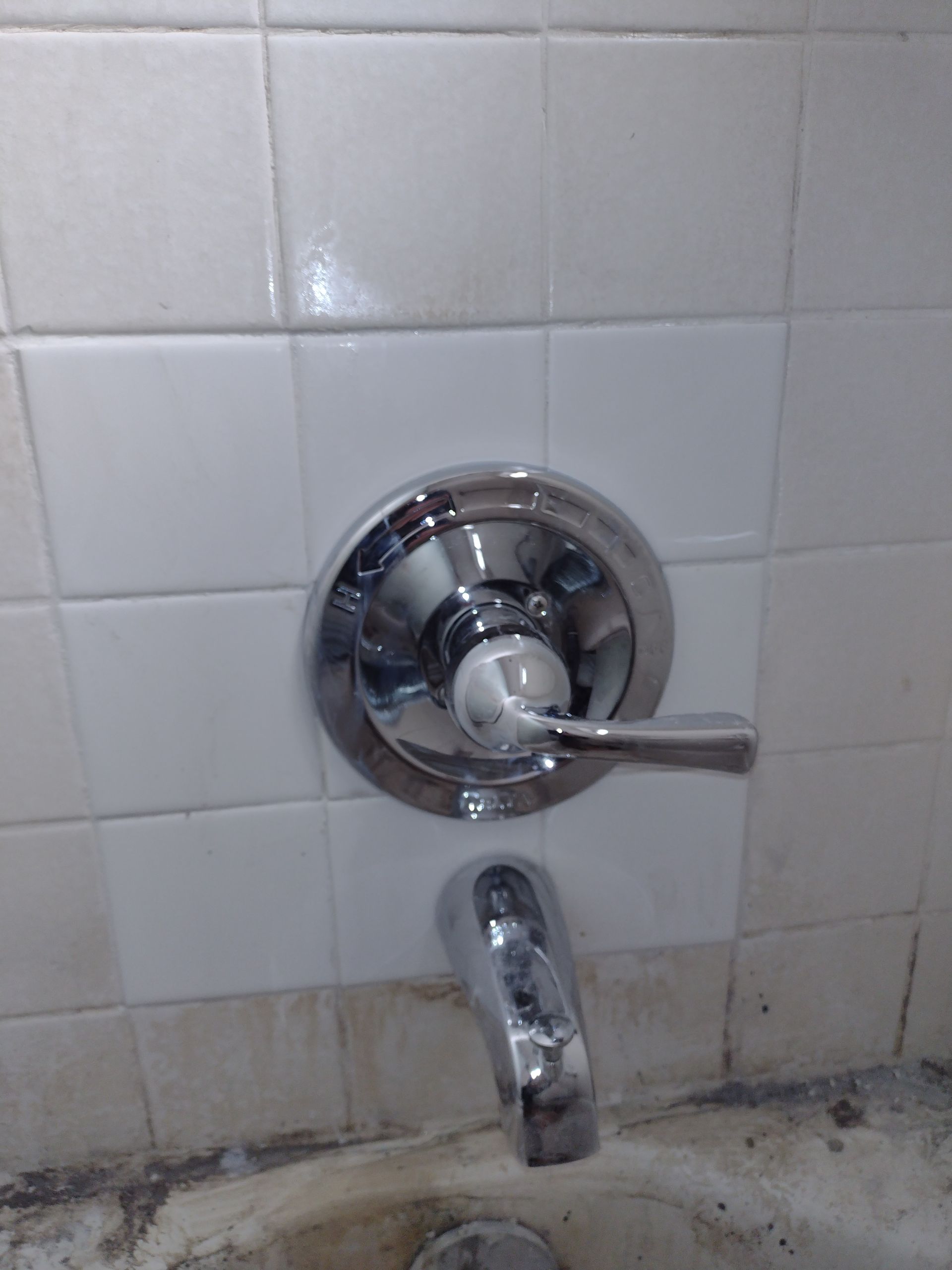 A close up of a shower faucet in a bathroom.