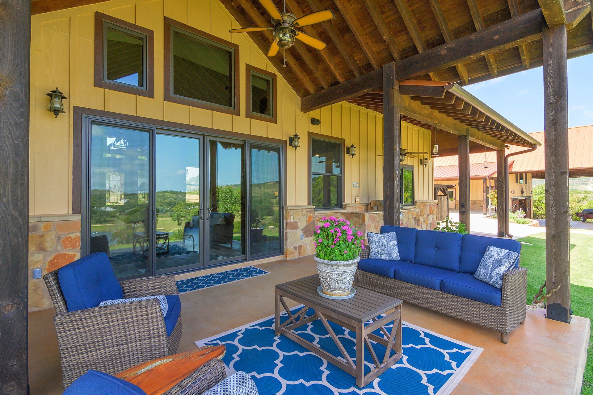 A patio with a couch , chairs and a table under a ceiling fan.