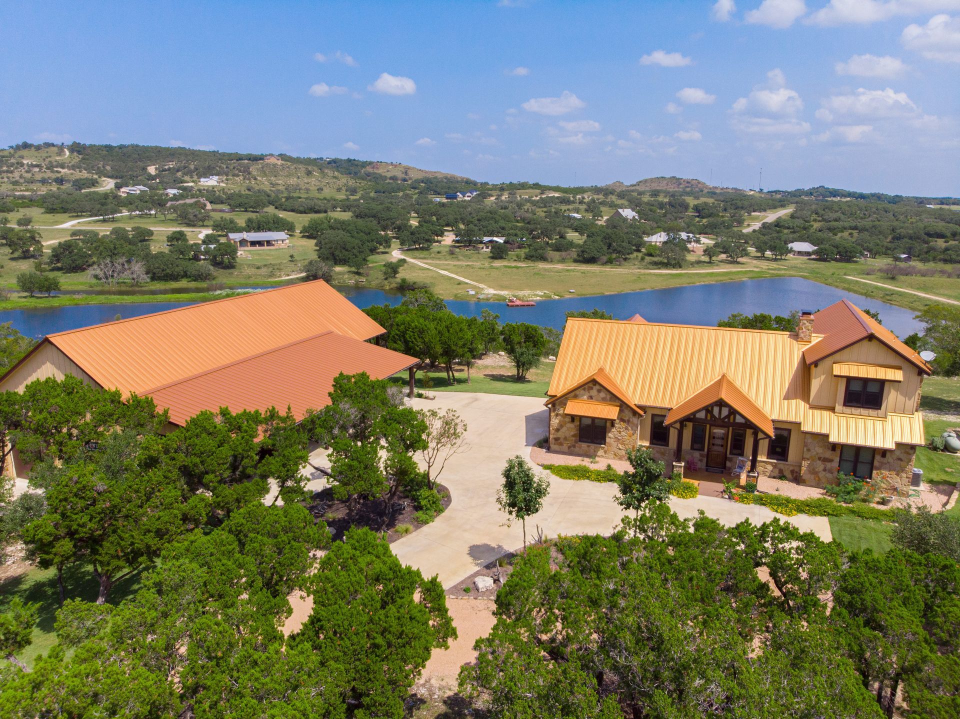 An aerial view of a large house surrounded by trees and a lake.
