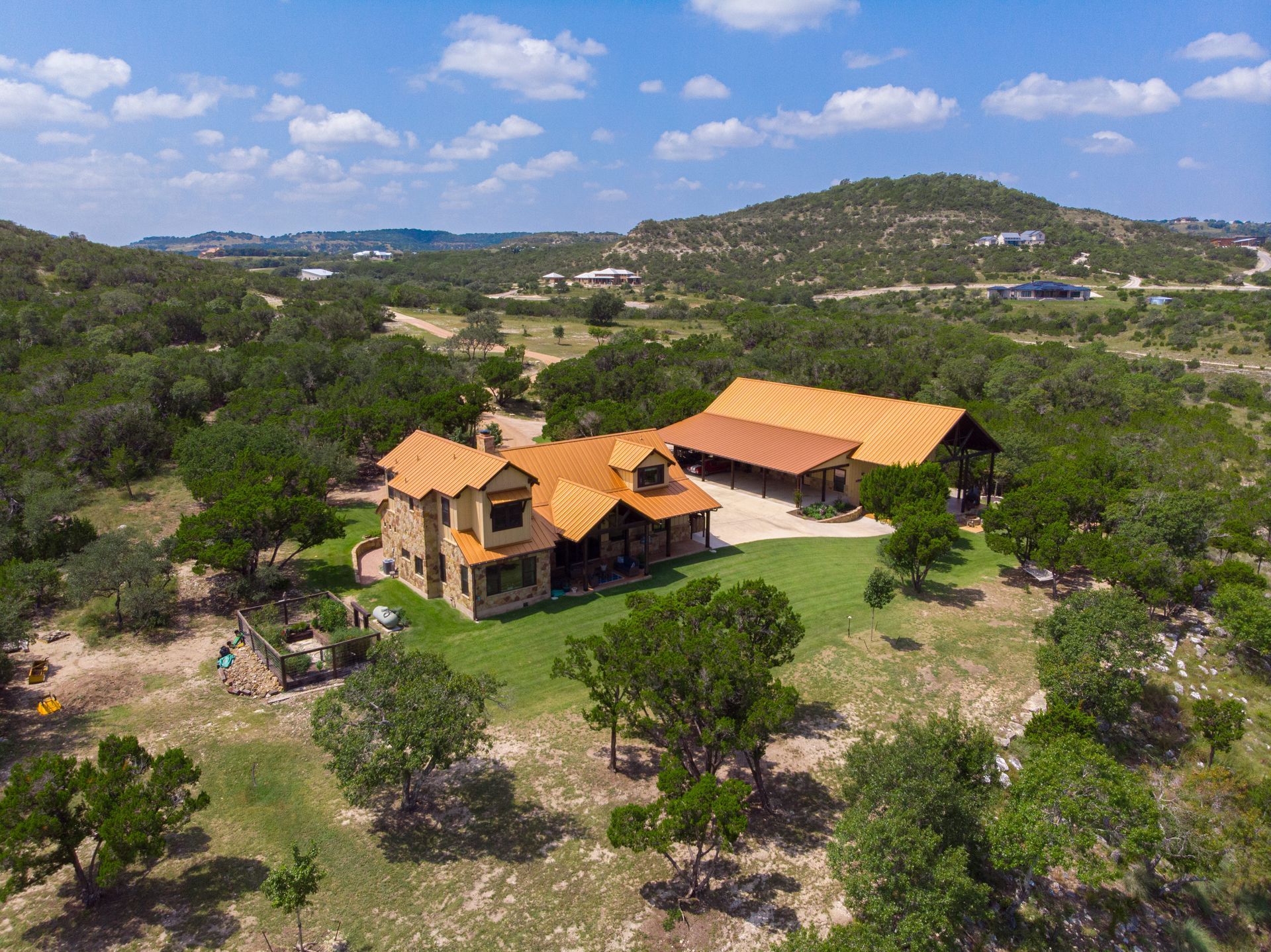 An aerial view of a large house surrounded by trees on top of a hill.
