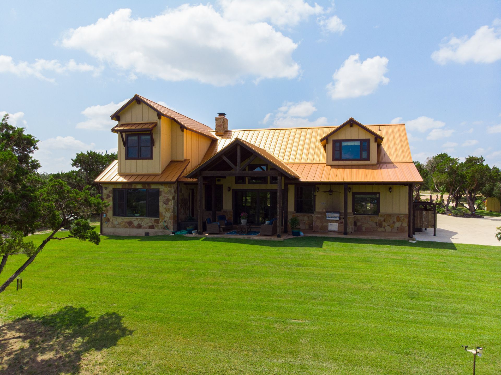 A large house with a copper roof is sitting on top of a lush green field.
