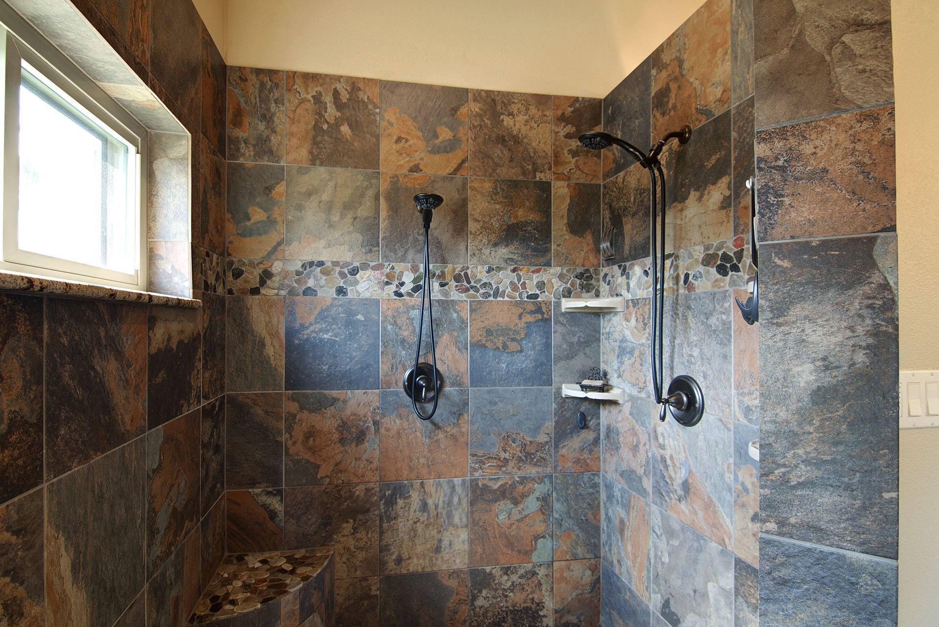 A walk in shower with two shower heads and a window.