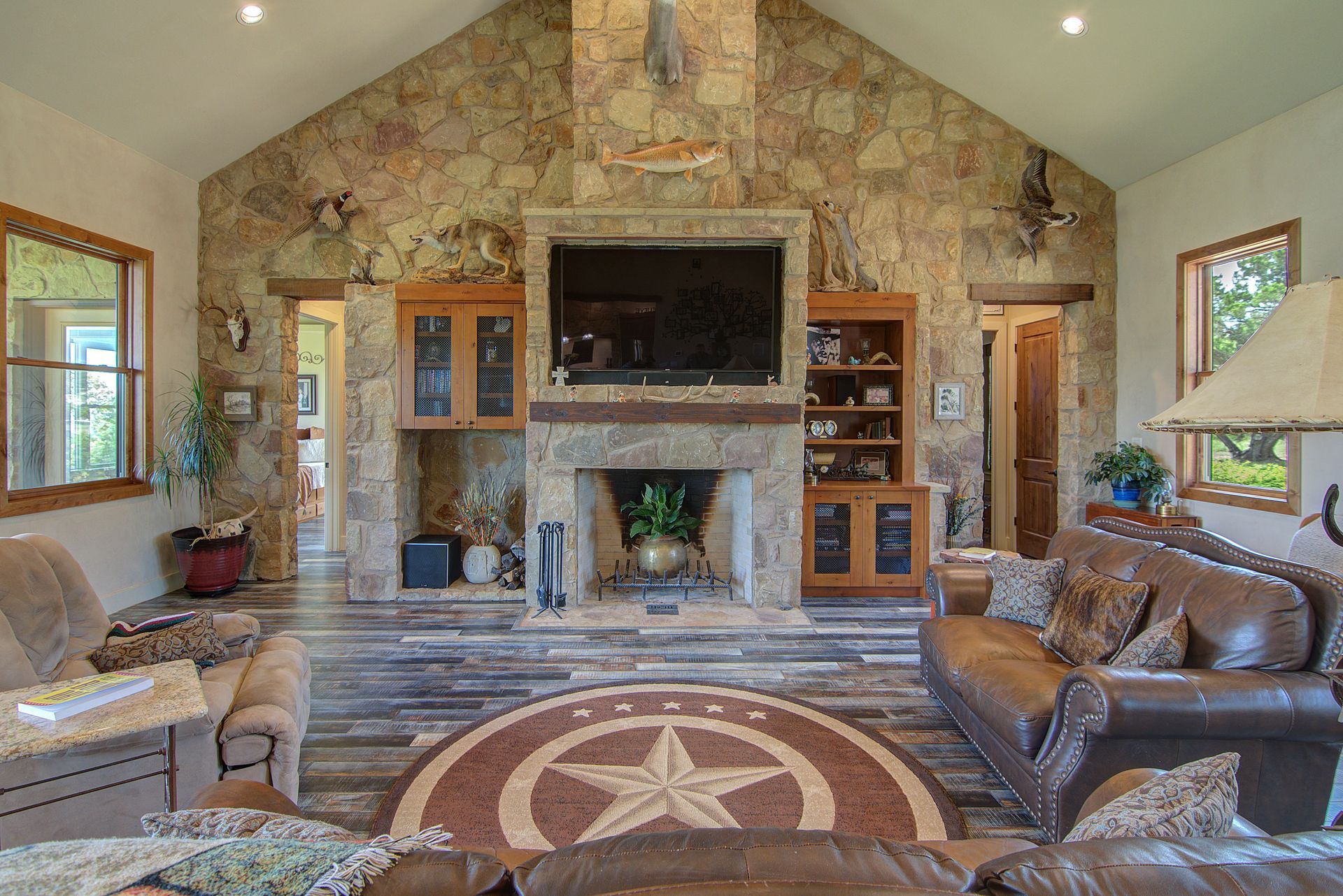A living room with a couch , chairs , fireplace and television.