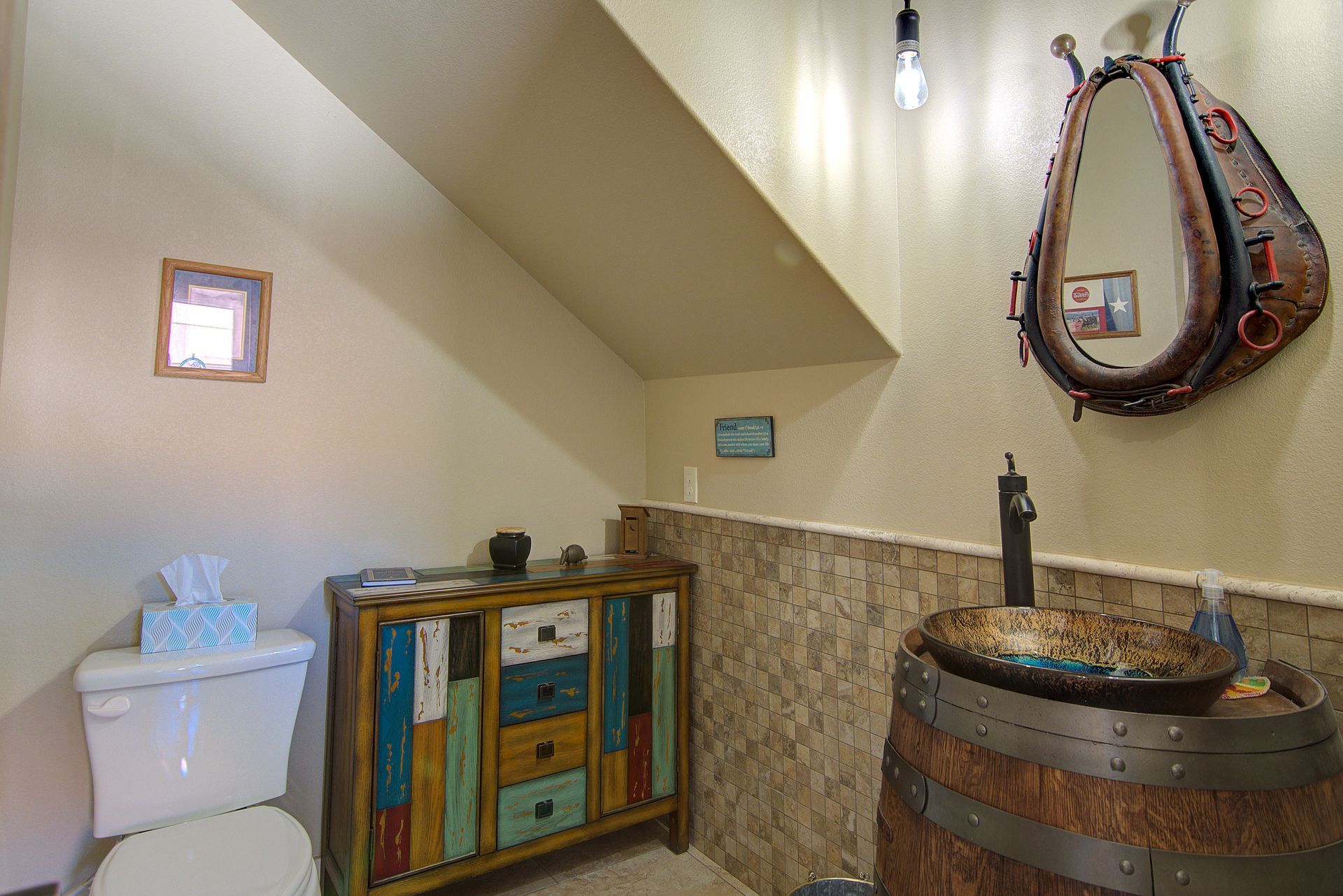 A bathroom with a toilet , sink , mirror and dresser.