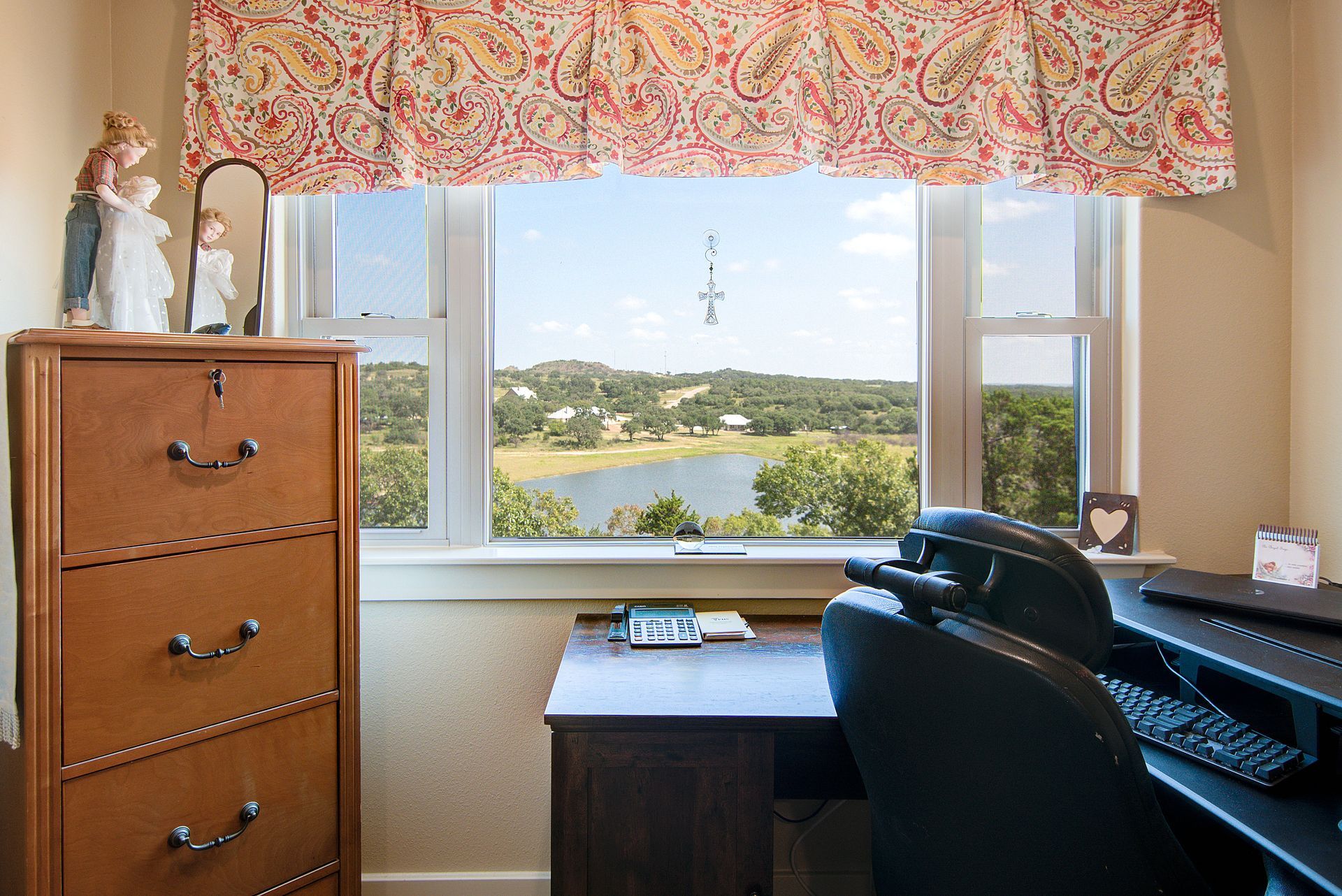 A room with a desk and chair and a window with a view of a lake