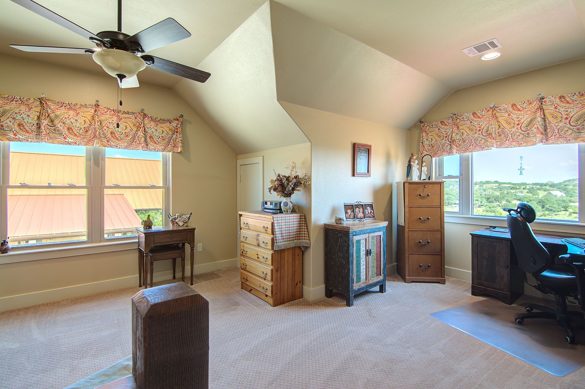A bedroom with a ceiling fan and a desk