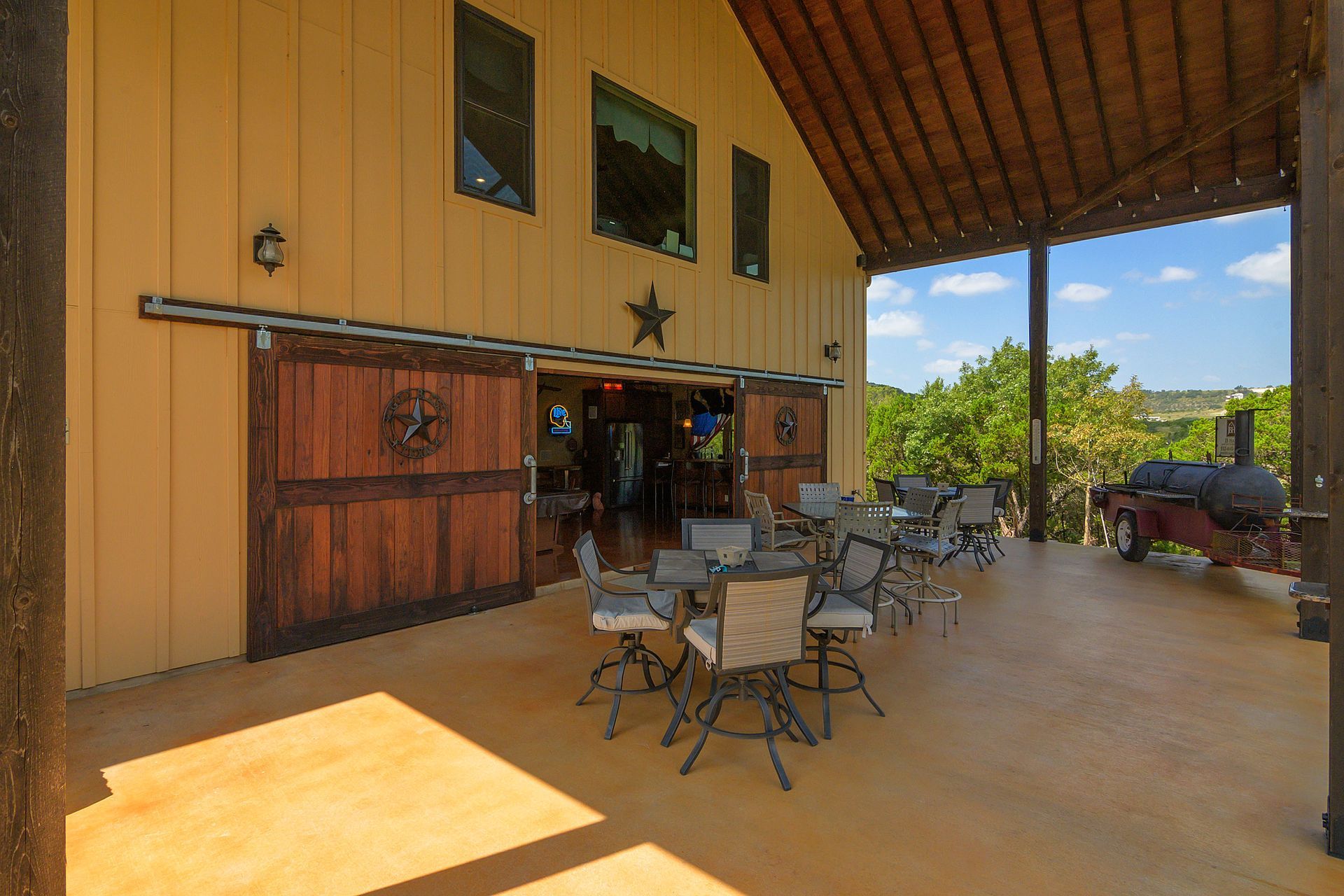 A large barn with tables and chairs in front of it.