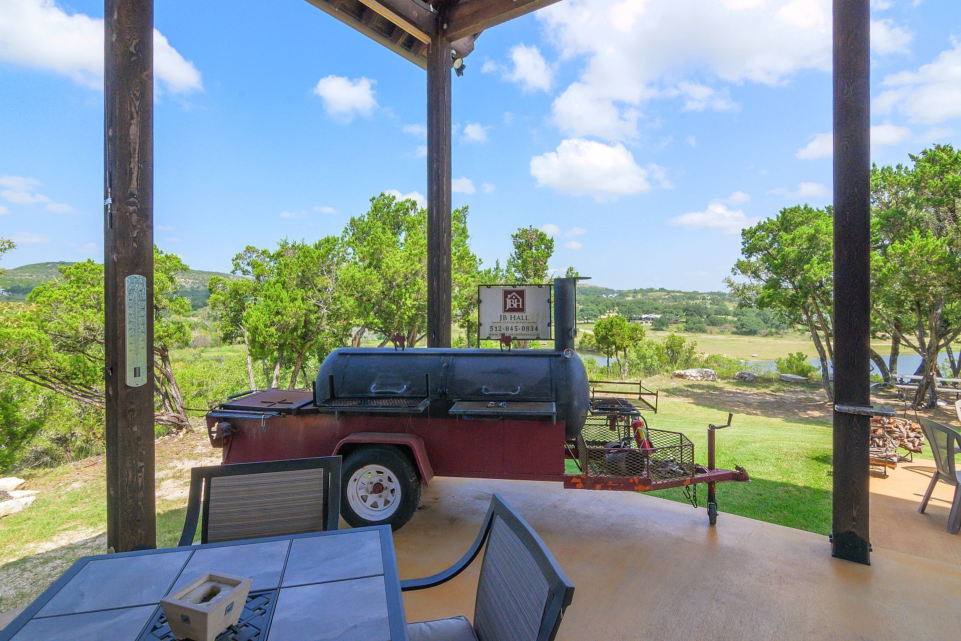 A patio with a table and chairs and a bbq on a trailer.
