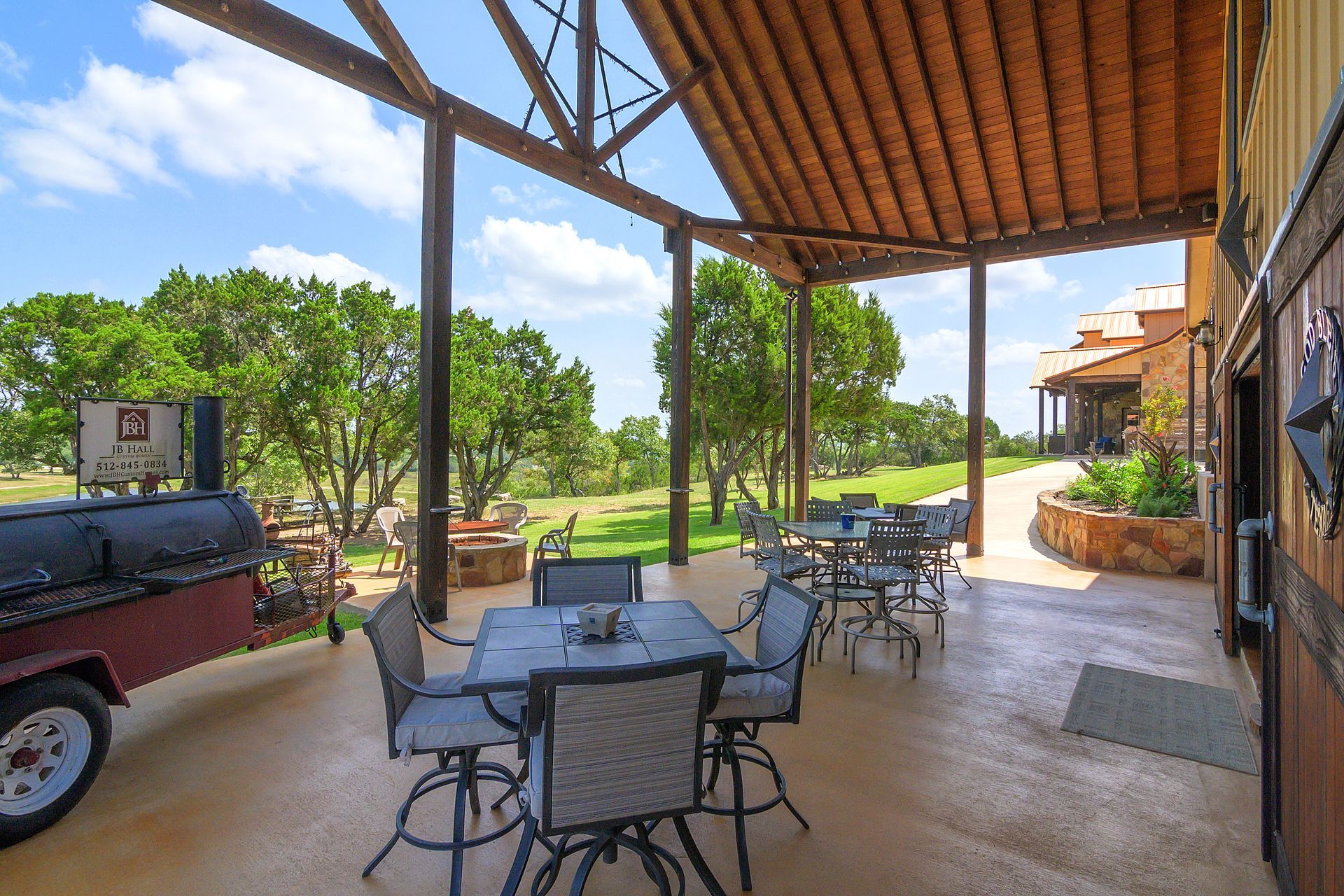 A patio with tables and chairs under a wooden roof.