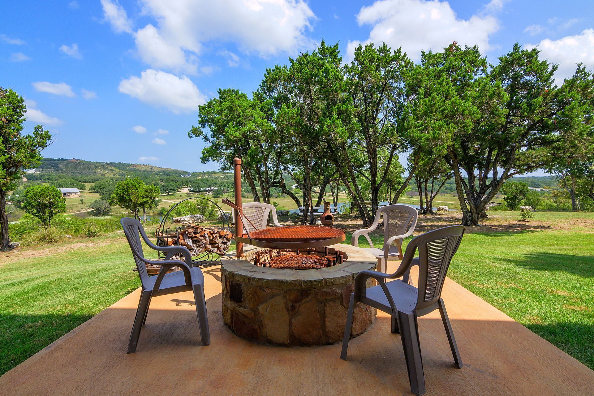 There is a fire pit in the middle of the yard with chairs around it.