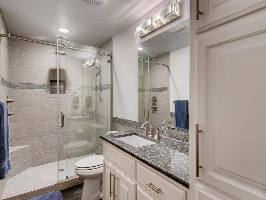 A bathroom with a sink , toilet , shower and mirror.