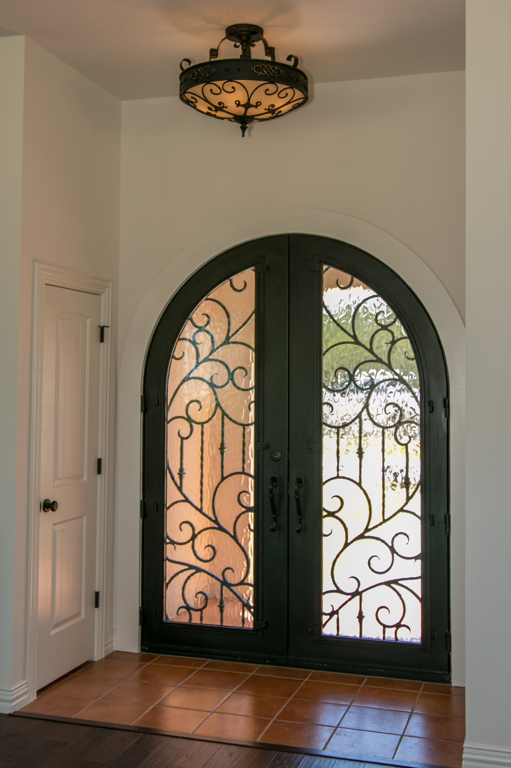 A wrought iron door with a chandelier above it
